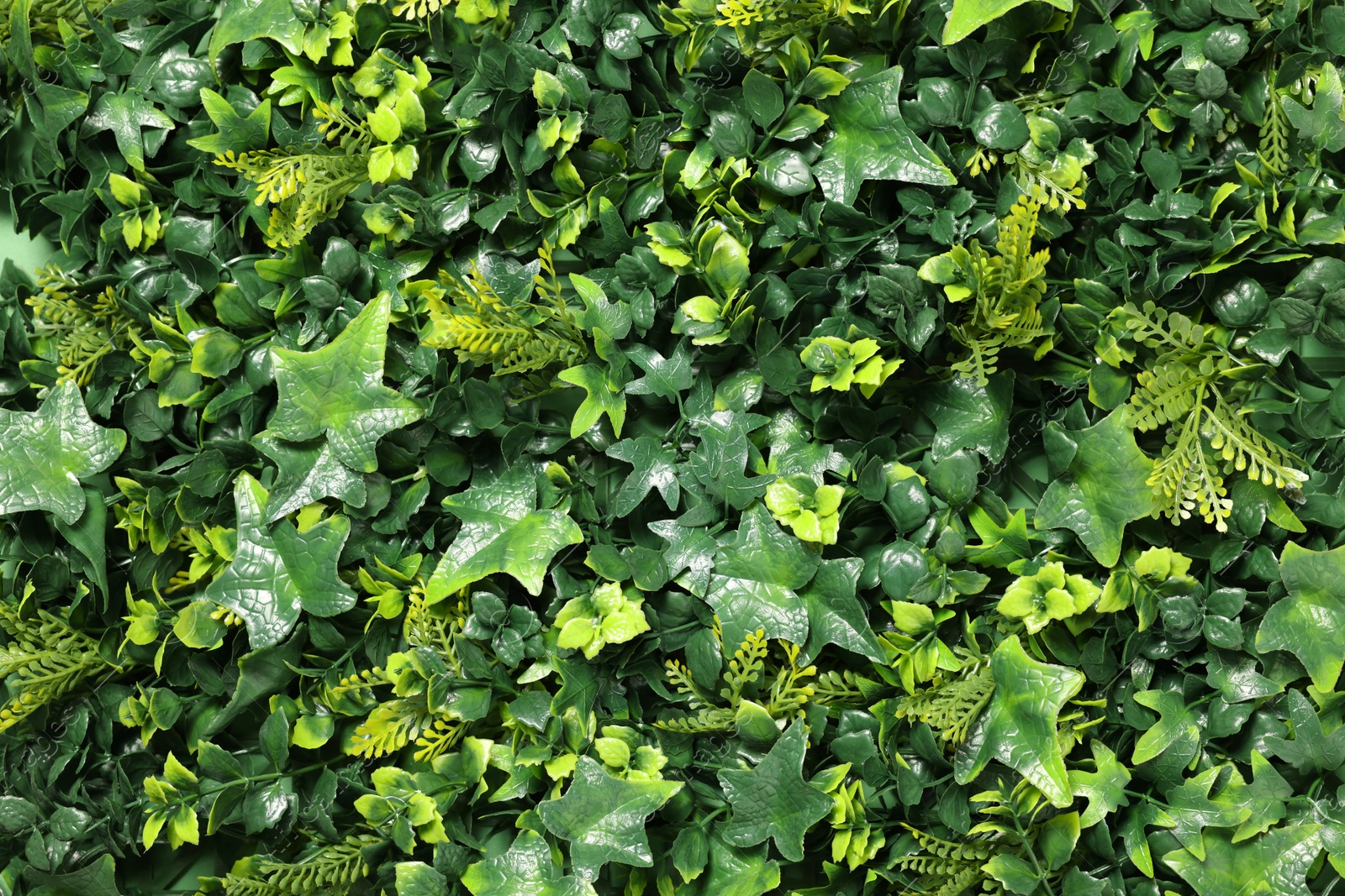 Photo of Green artificial plants as background, closeup view