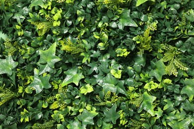 Green artificial plants as background, closeup view