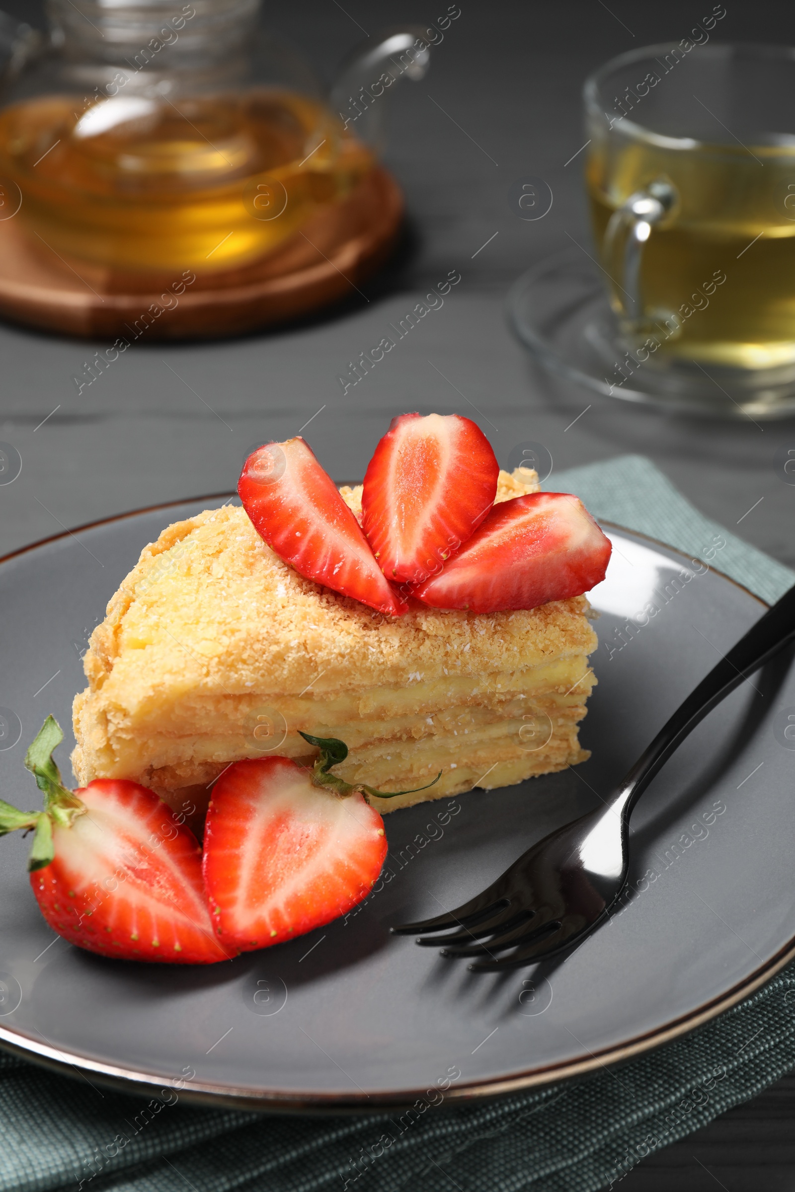 Photo of Piece of delicious Napoleon cake with strawberries on table