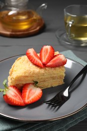 Photo of Piece of delicious Napoleon cake with strawberries on table