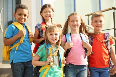 Photo of Cute little children with backpacks outdoors. Elementary school