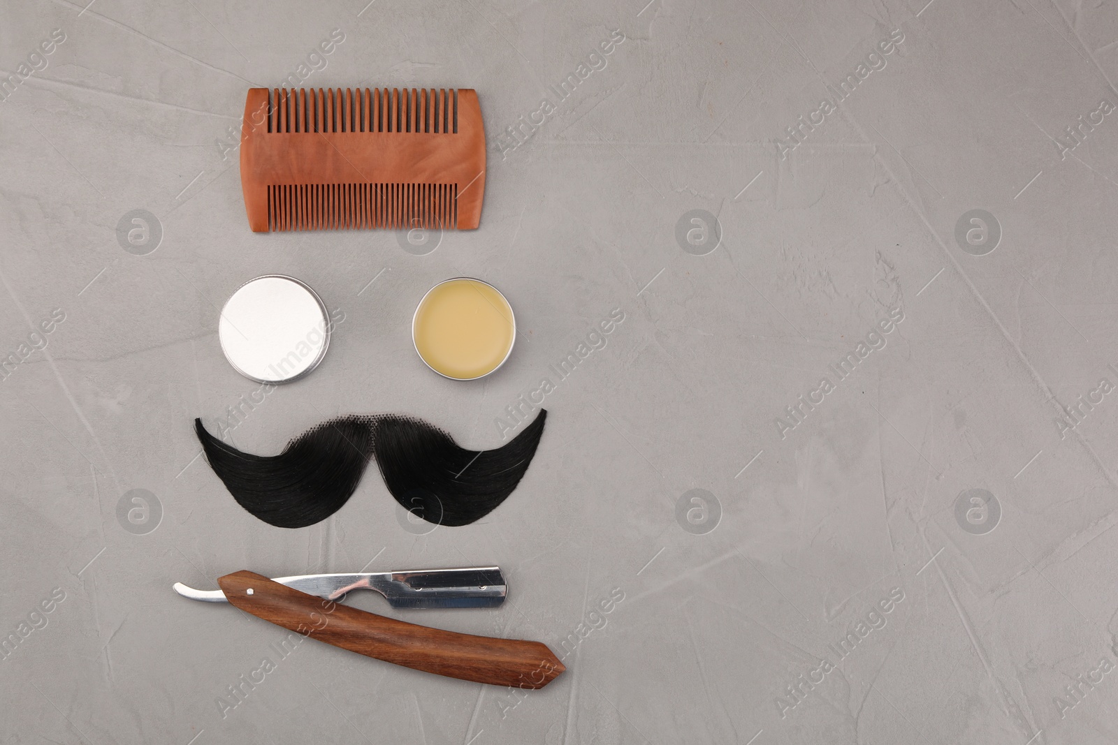 Photo of Artificial moustache and barber tools on grey table, flat lay. Space for text