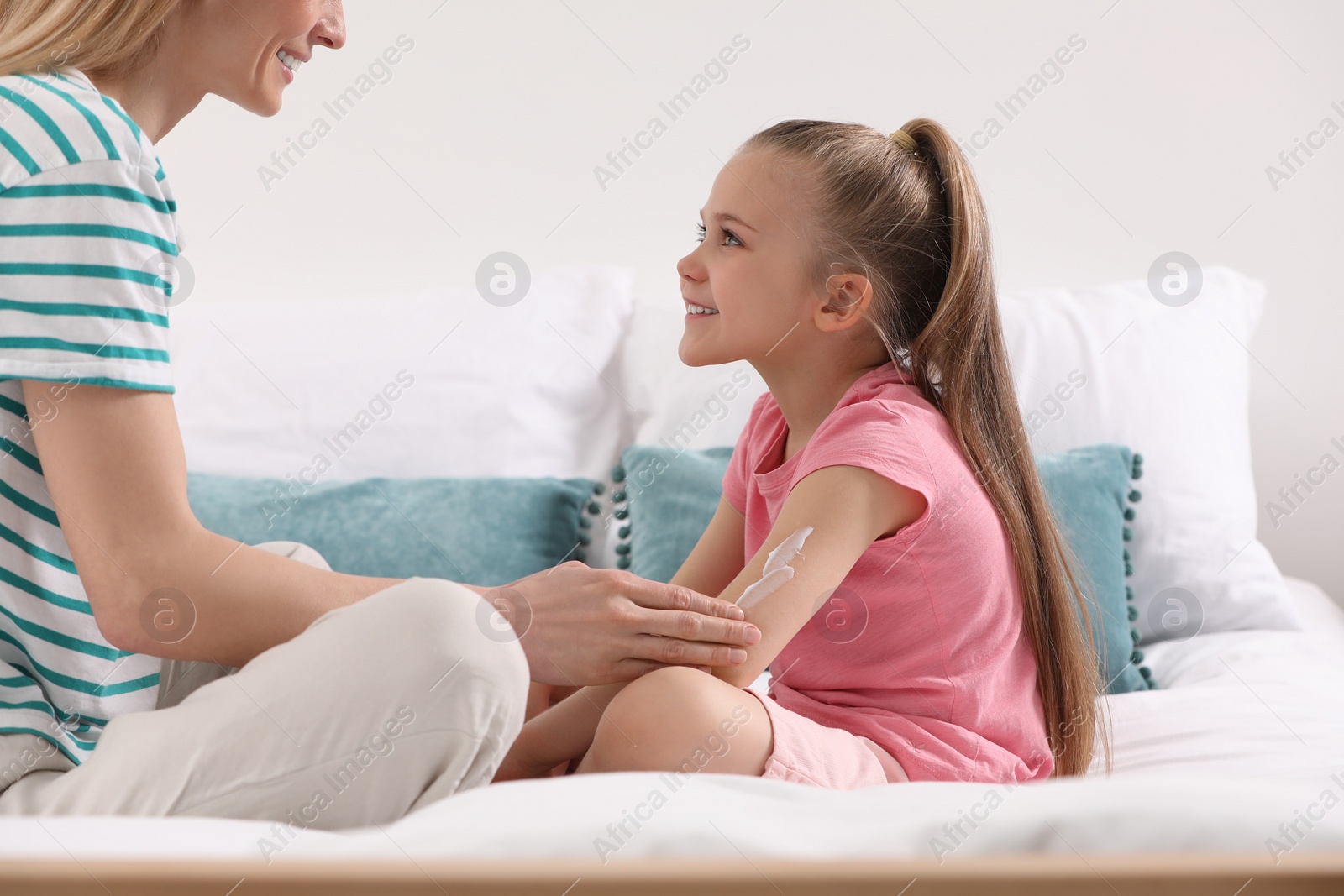 Photo of Mother applying ointment onto her daughter's hand on bed