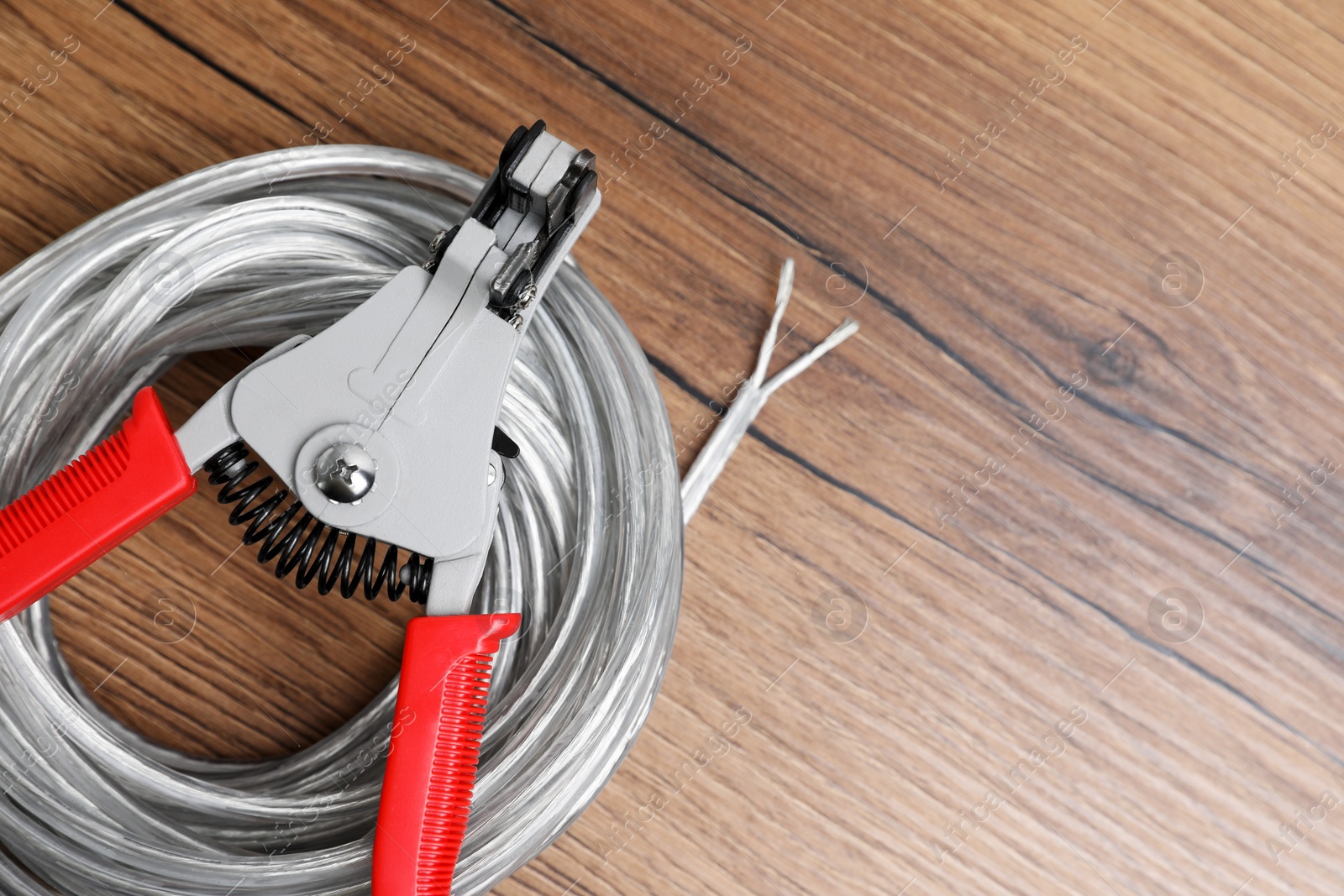 Photo of Cutters and cable with stripped wire on wooden table, top view. Space for text