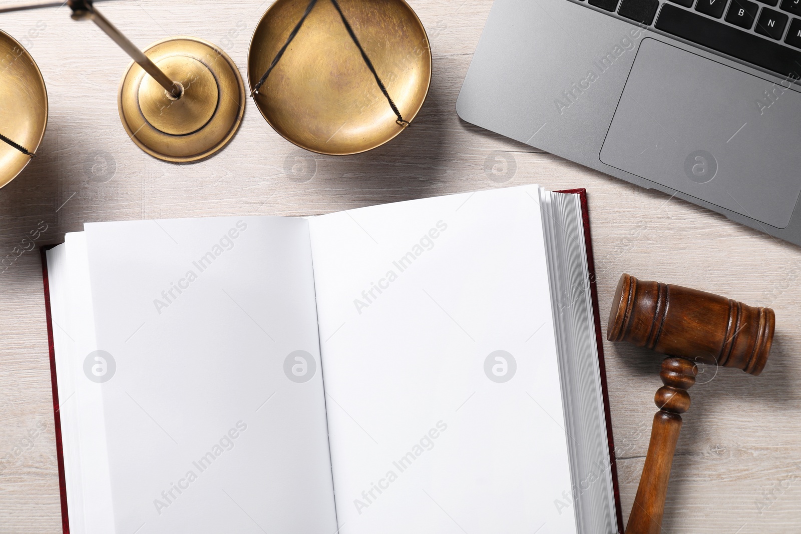 Photo of Law. Open book, gavel, laptop and scales on wooden table, flat lay