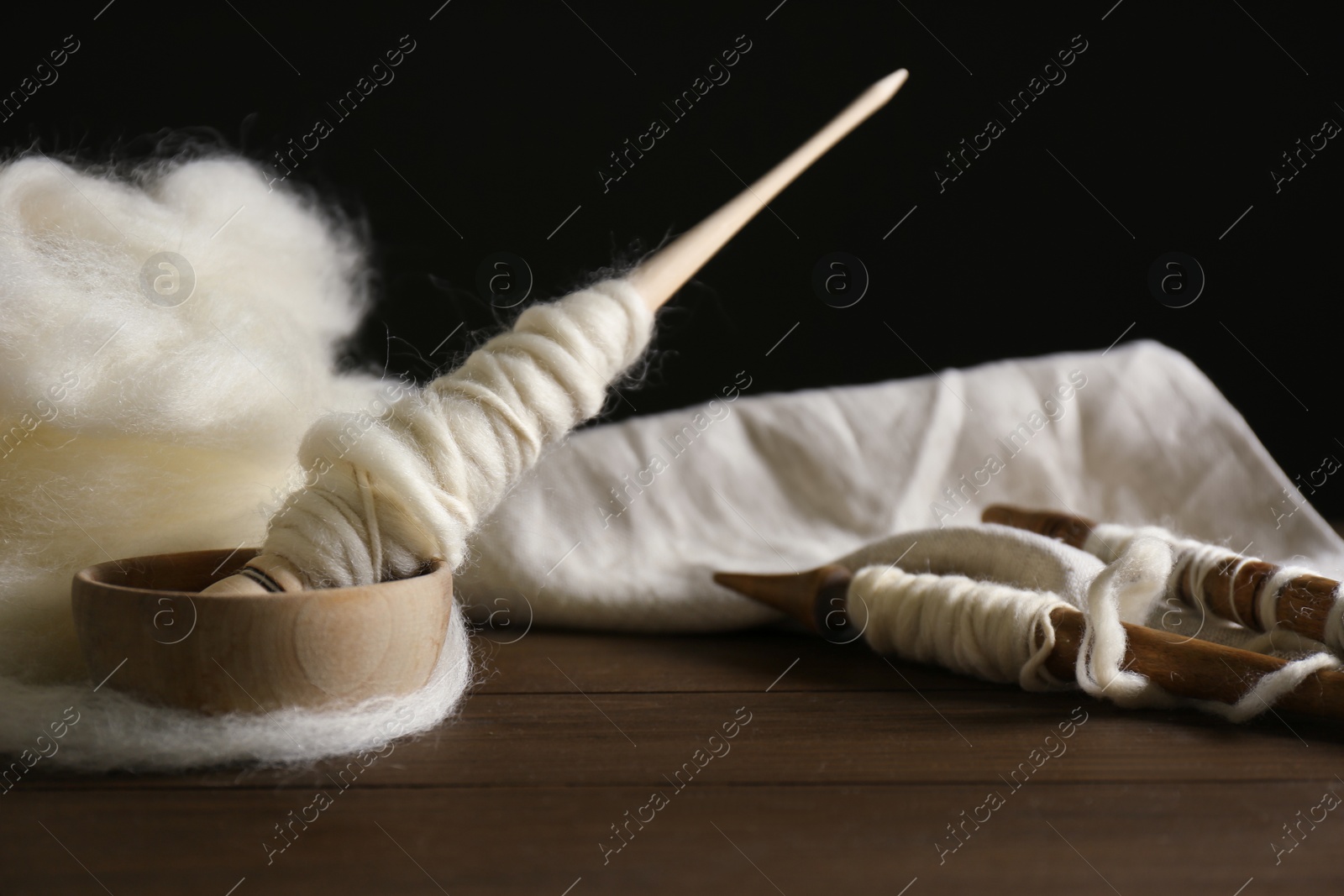 Photo of Spindles and soft white wool on wooden table