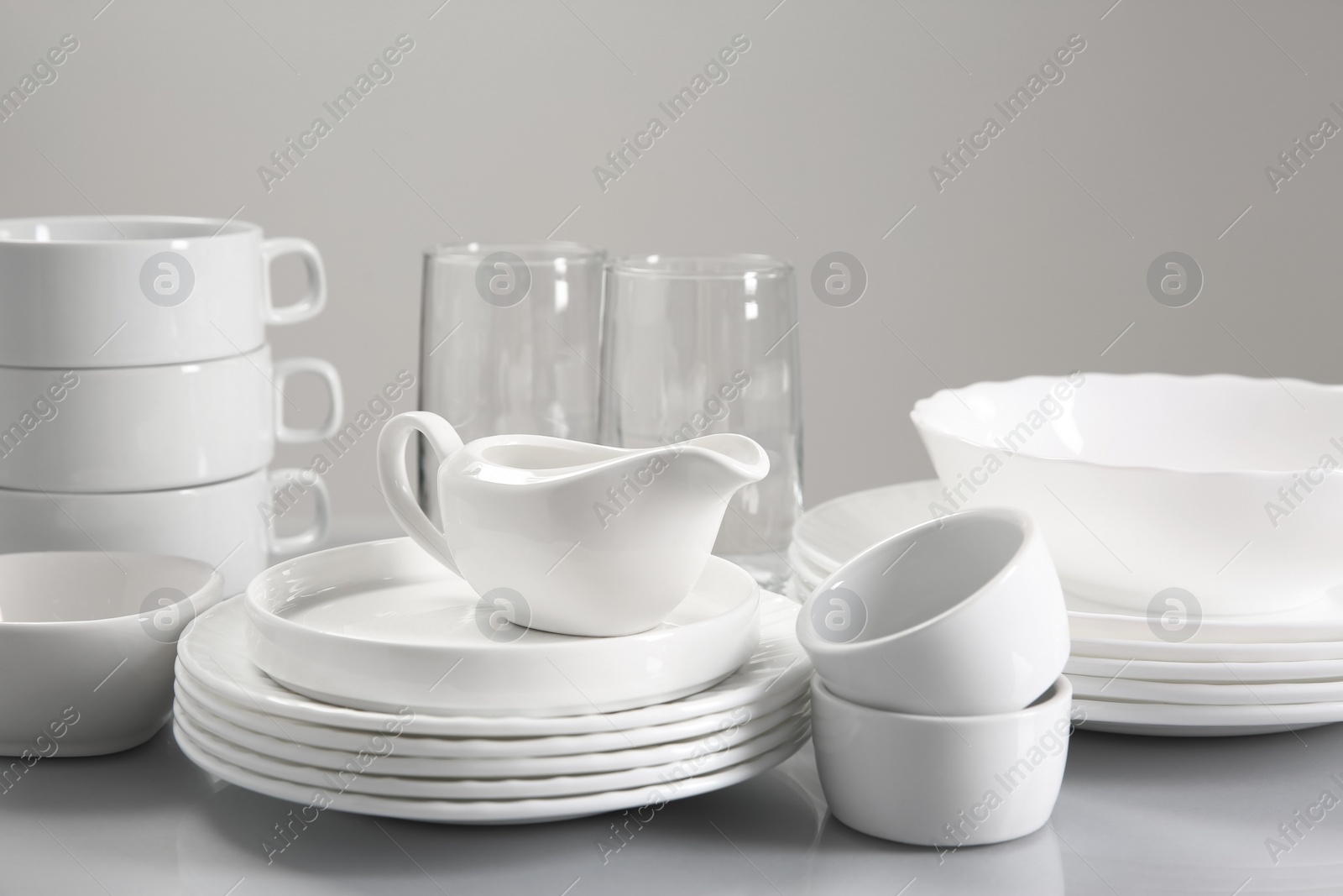 Photo of Set of many clean dishware and glasses on light table