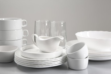 Photo of Set of many clean dishware and glasses on light table