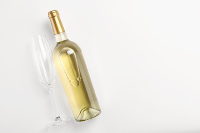 Photo of Bottle of expensive white wine and wineglass on light background, top view. Space for text