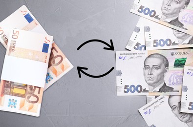 Currency exchange. Circle arrows between hryvnias and euro banknotes on grey background, flat lay