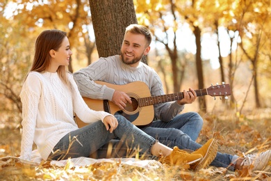 Young couple with guitar in autumn park