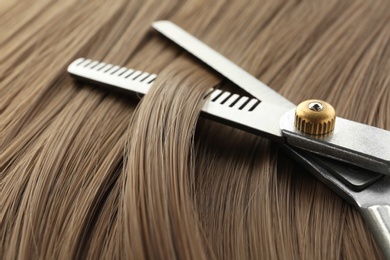 Photo of Thinning scissors on light brown hair, closeup. Hairdresser service