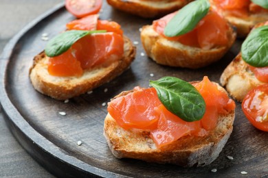 Delicious sandwiches with salmon and spinach on wooden board, closeup