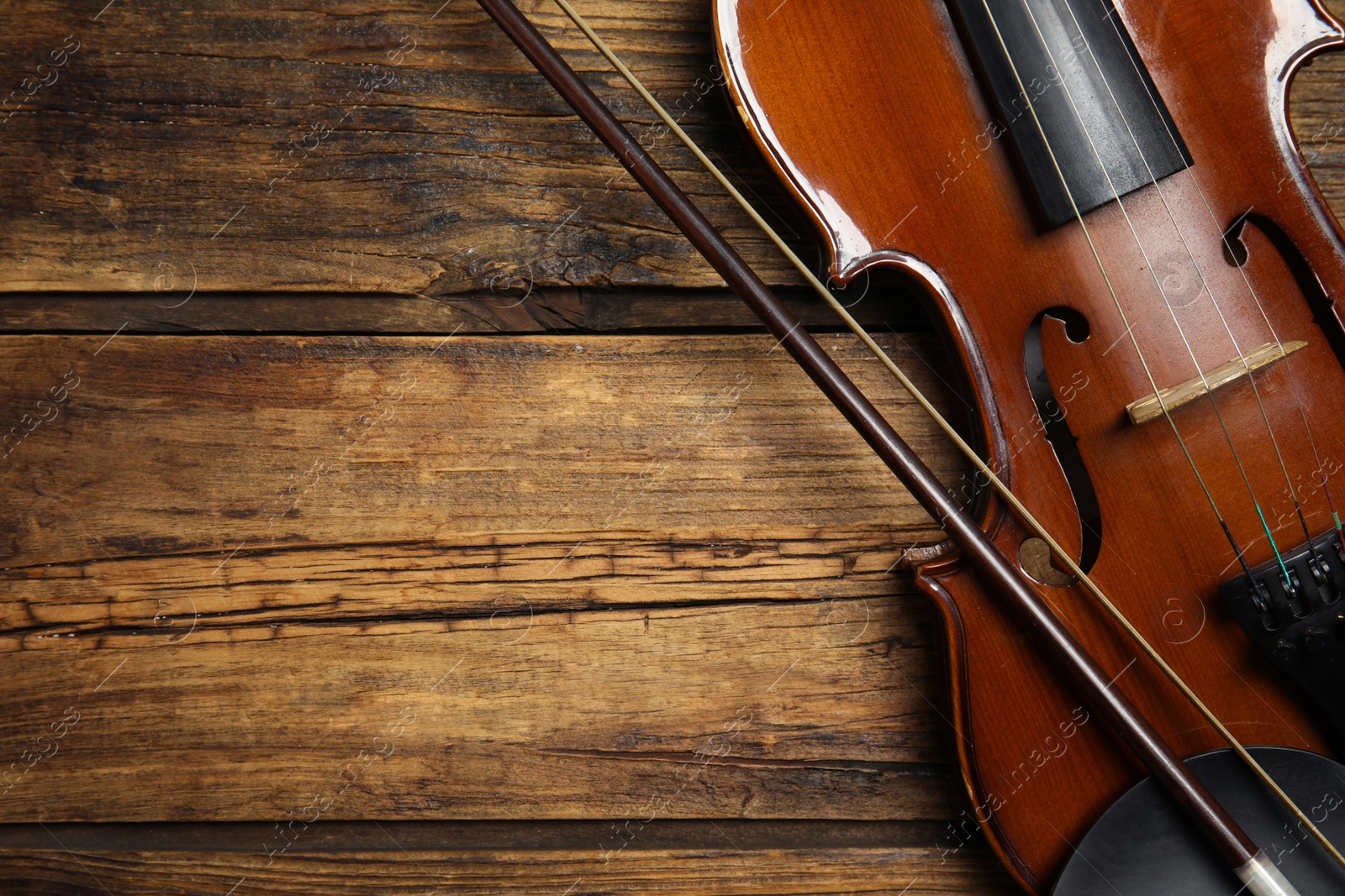 Photo of Classic violin and bow on wooden background, top view. Space for text