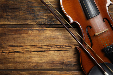 Classic violin and bow on wooden background, top view. Space for text