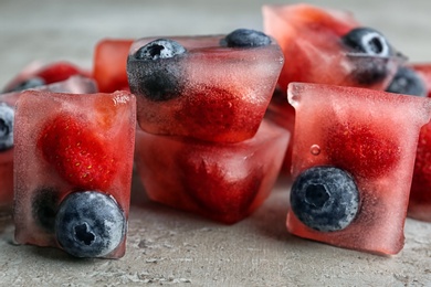 Photo of Ice cubes with berries on table, closeup