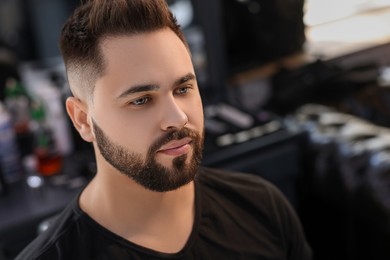 Photo of Handsome young man with fresh haircut and groomed beard in barbershop