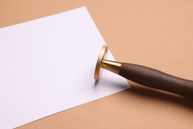 One stamp tool and sheet of paper on light brown background, closeup