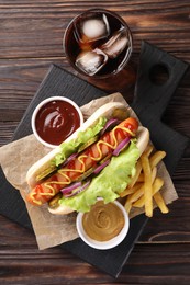 Delicious hot dog with lettuce, onion and pickle served on wooden table, top view