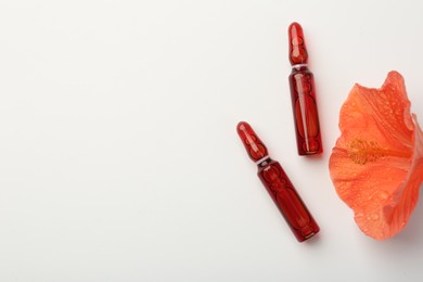 Skincare ampoules and hibiscus flower with water drops on white background, flat lay. Space for text