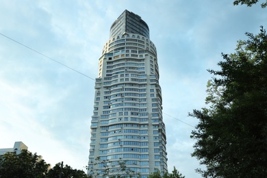 Photo of KYIV, UKRAINE - MAY 23, 2019: Modern dwelling building against sky with clouds