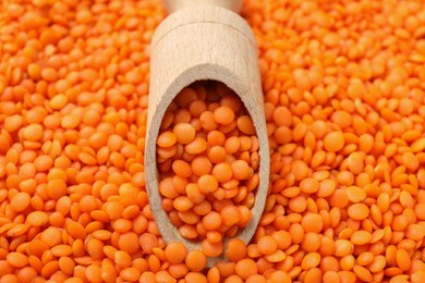 Photo of Heap of raw lentils and wooden scoop, closeup view