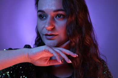 Portrait of beautiful young woman on color background with neon lights