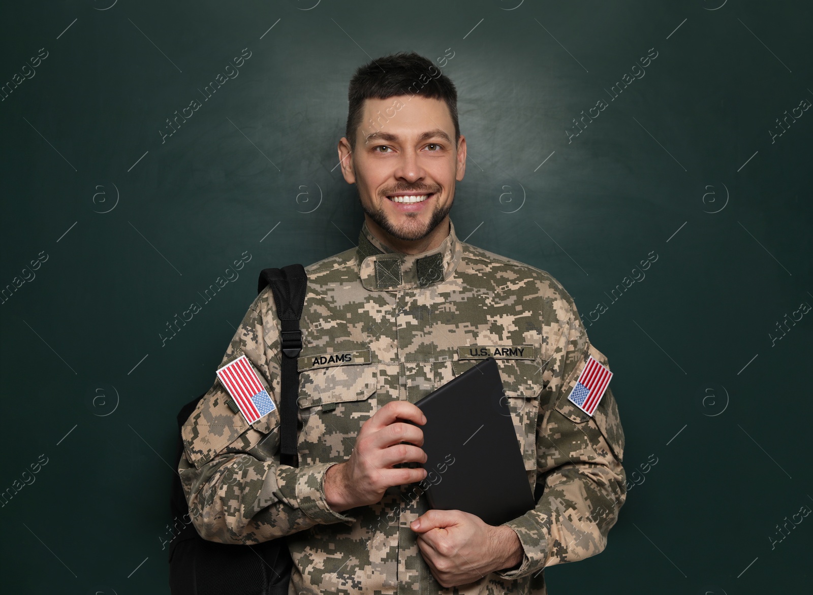 Photo of Cadet with backpack and tablet near chalkboard. Military education