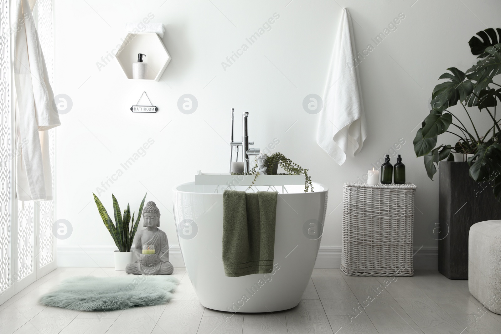 Photo of Stylish bathroom interior with modern tub, houseplants and beautiful decor. Home design