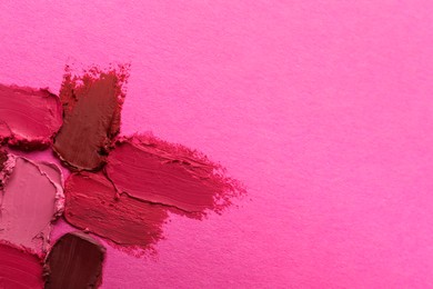 Photo of Smears of beautiful lipsticks on pink background, top view. Space for text