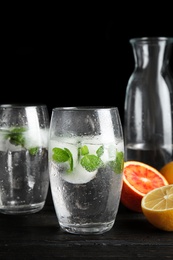 Photo of Composition with refreshing drink with mint and ice cubes in glasses on dark table. Space for text