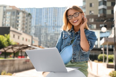 Beautiful woman using laptop in city on sunny day