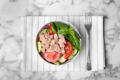 Photo of Delicious salad with canned tuna in bowl on marble background, top view