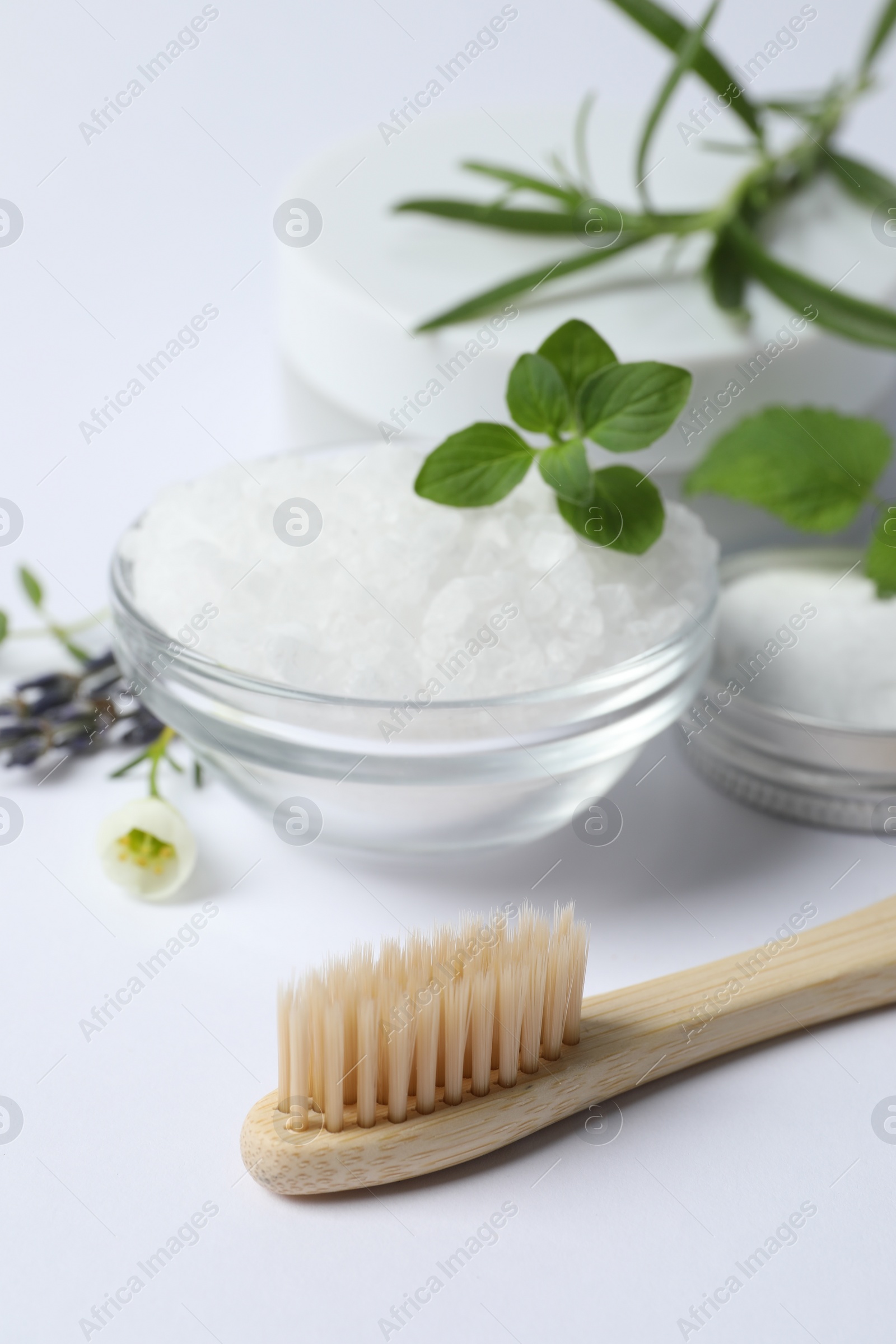 Photo of Toothbrush, sea salt, dry flowers and green herbs on white background, closeup