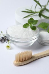 Toothbrush, sea salt, dry flowers and green herbs on white background, closeup