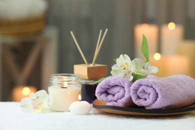 Photo of Beautiful composition with different spa products and flowers on white towel against blurred background