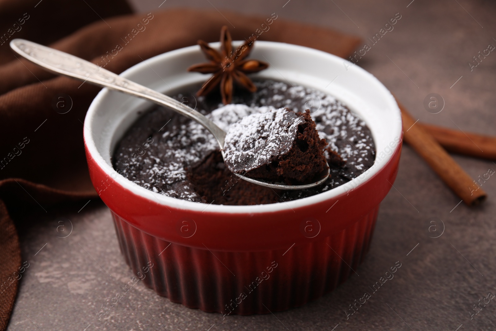 Photo of Tasty chocolate pie with anise and spoon on brown table, closeup. Microwave cake recipe