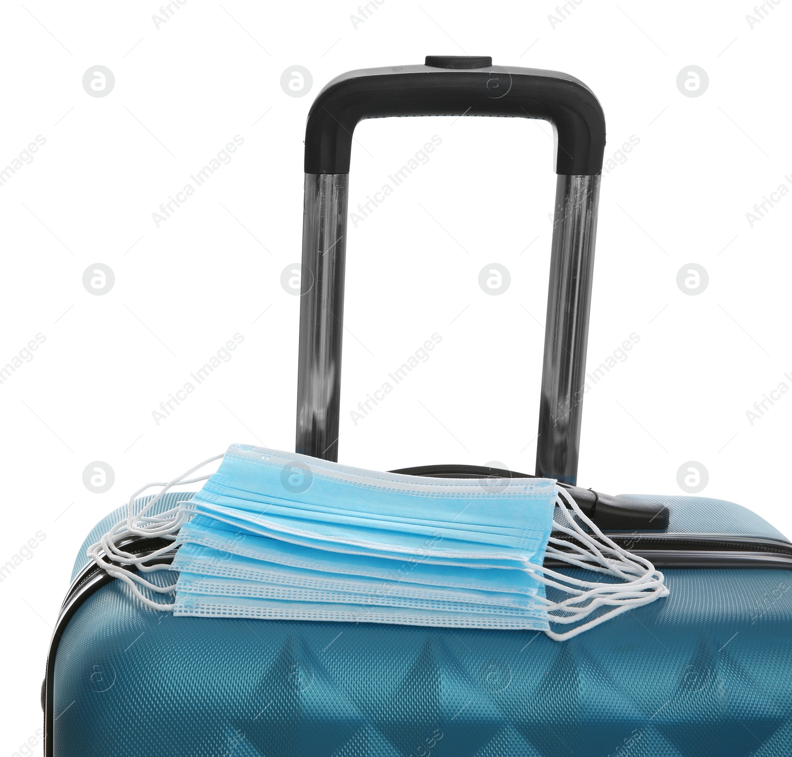 Photo of Stylish blue suitcase and protective masks on white background. Travelling during coronavirus pandemic