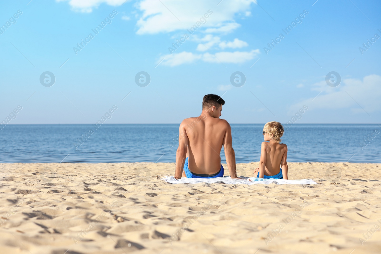 Photo of Father and son on sandy beach near sea, space for text. Summer holidays with family