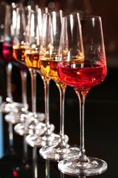Photo of Row of glasses with different wines on table against blurred background