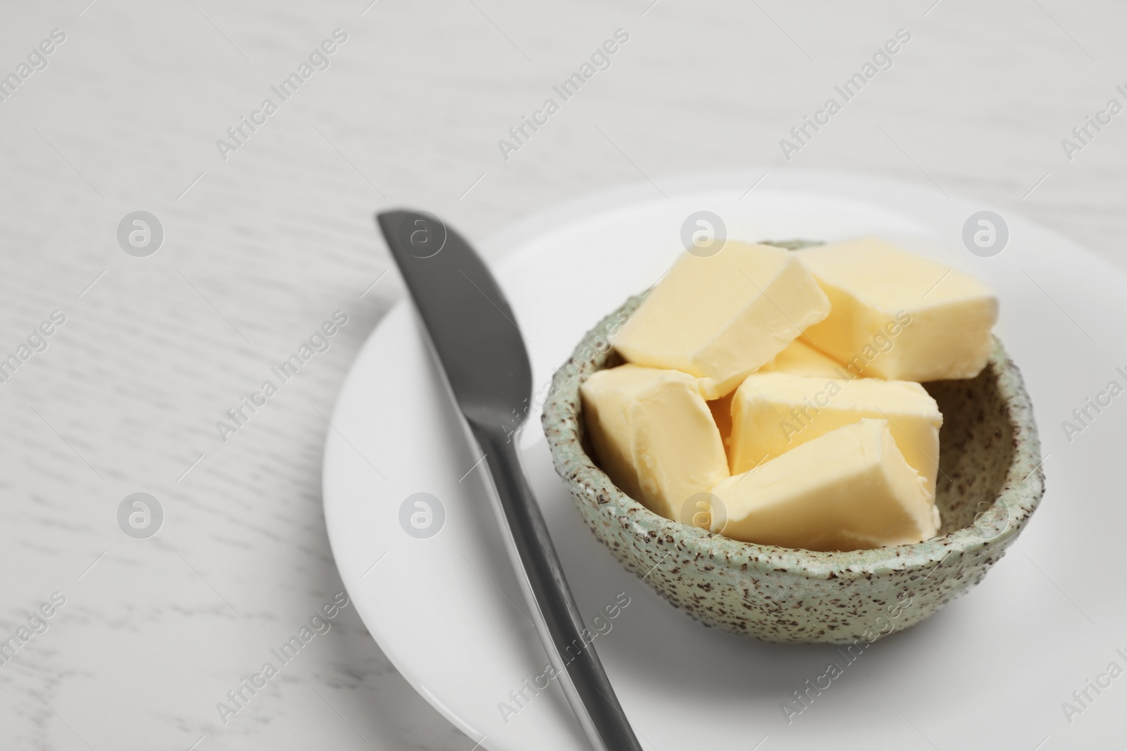 Photo of Bowl with tasty fresh butter and knife on wooden table