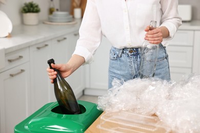 Woman separating garbage at table indoors, closeup