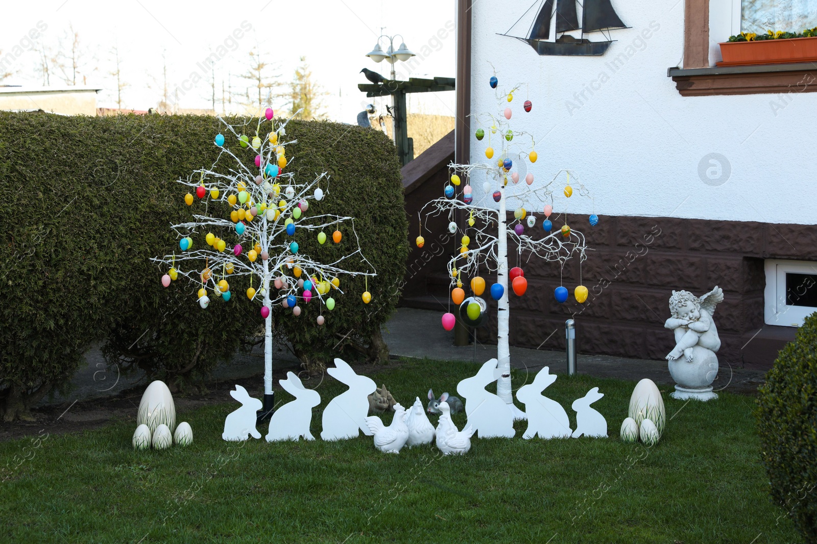 Photo of Trees with decorative eggs, chickens and bunnies at backyard. Easter celebration