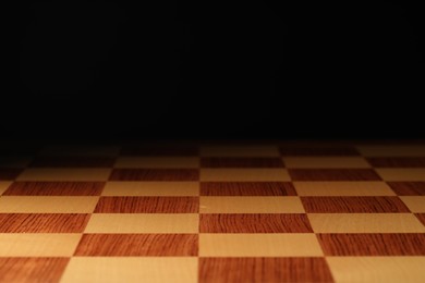 Photo of Checkered chessboard on dark background, closeup view