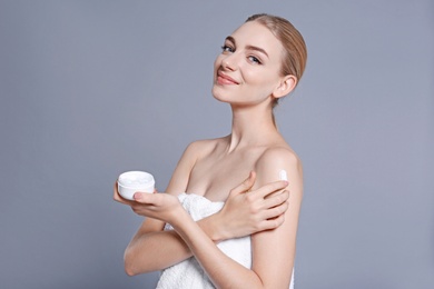 Photo of Young woman with jar of body cream on color background