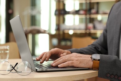 Man working on laptop at table in cafe, closeup