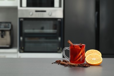 Photo of Aromatic punch drink and ingredients on grey table in kitchen. Space for text