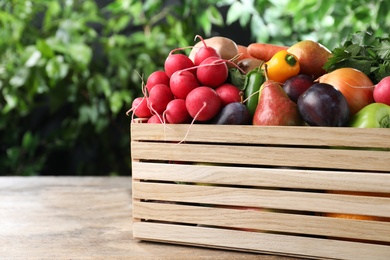 Photo of Crate full of different vegetables and fruits on wooden table outdoors. Harvesting time