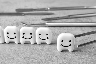 Photo of Composition with small plastic teeth and professional tools on grey table