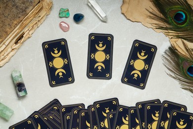 Photo of Tarot cards, peacock feathers, gemstones and old book on light table, flat lay. Reverse side